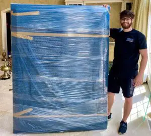 MVM Moving & Storage employee wrapping a large object to move within the house